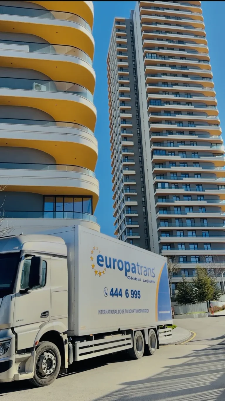 Konut girişinin yakınında konumlanan kapalı kasa kamyon, Europatrans ev taşıma araçlarından birini gösteriyor.